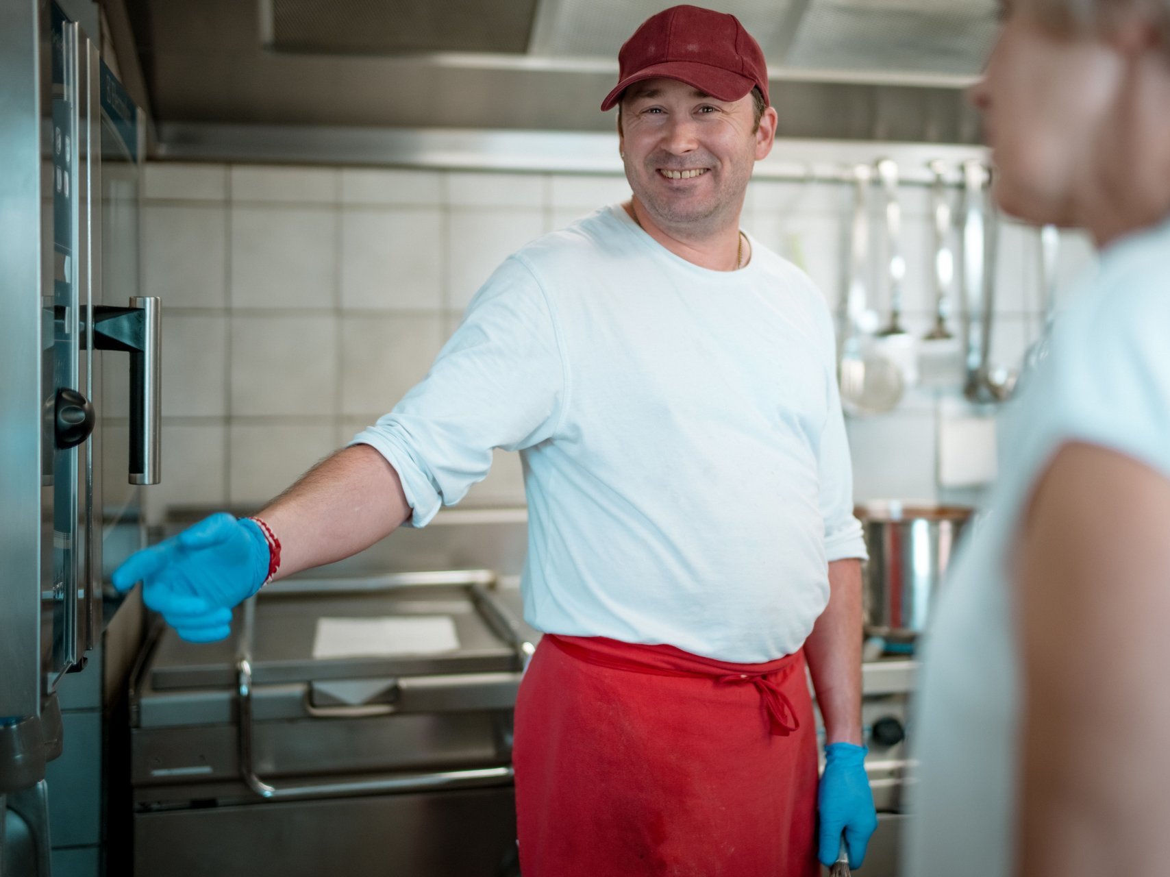 Mitarbeitender zeigt einer anderen Mitarbeitenden aus der Hauswirtschat auf einer Uhr wie lange das essen noch braucht.