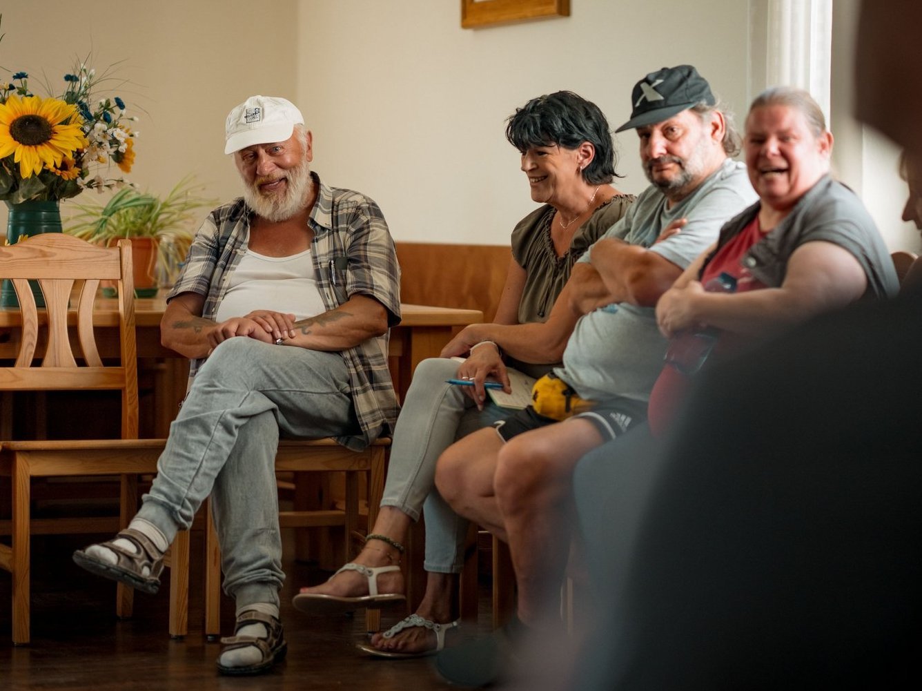 Eine Gruppe Bewohnende sitzen im Kreis, lachen und tauschen sich aus.