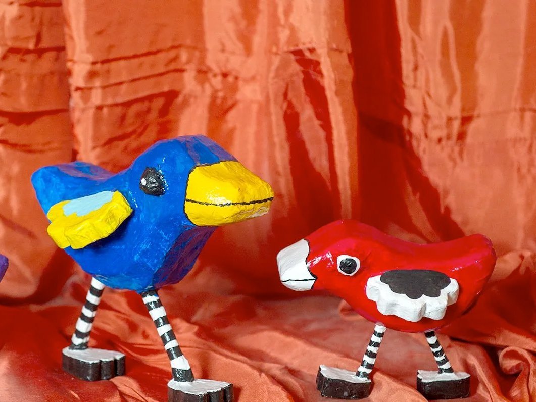 Nahaufnahme: stilisierte Vogel-Puppen aus Holz - farbenfroh bemalt