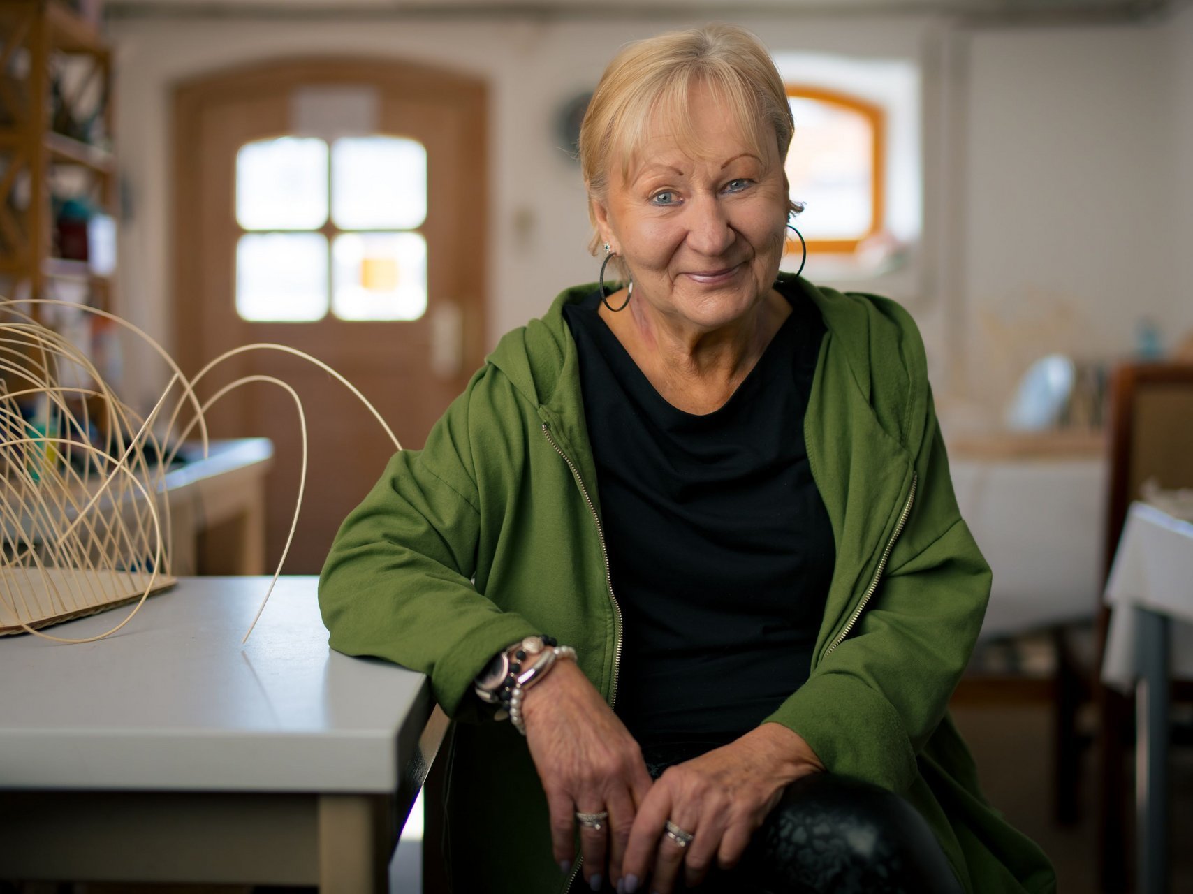 Eine Frau sitzt auf einem Stuhl und lehnt sich am Tisch ab.