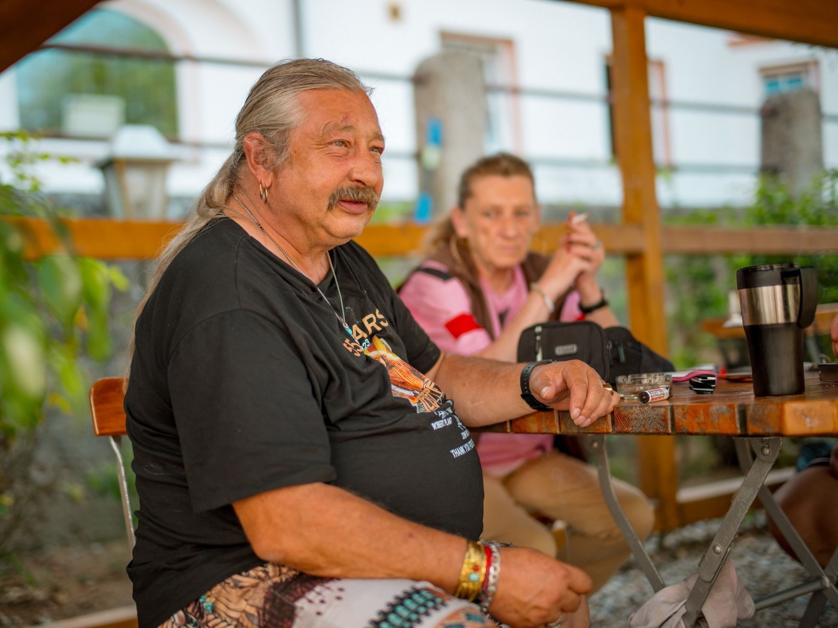 Ein Bewohnender sitzt mit einer Frau draußen an einem Tisch.