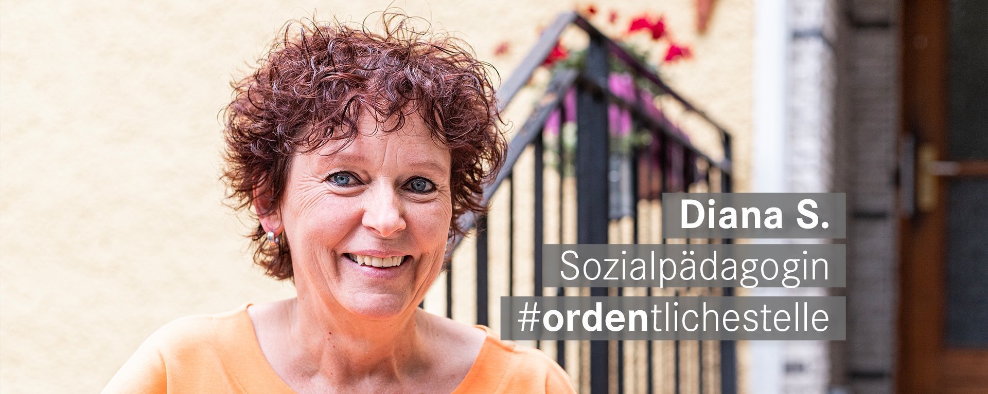 Sozialpaedagogin mit roten kurzen Locken und blauen Augen laechelt freundlich in die Kamera