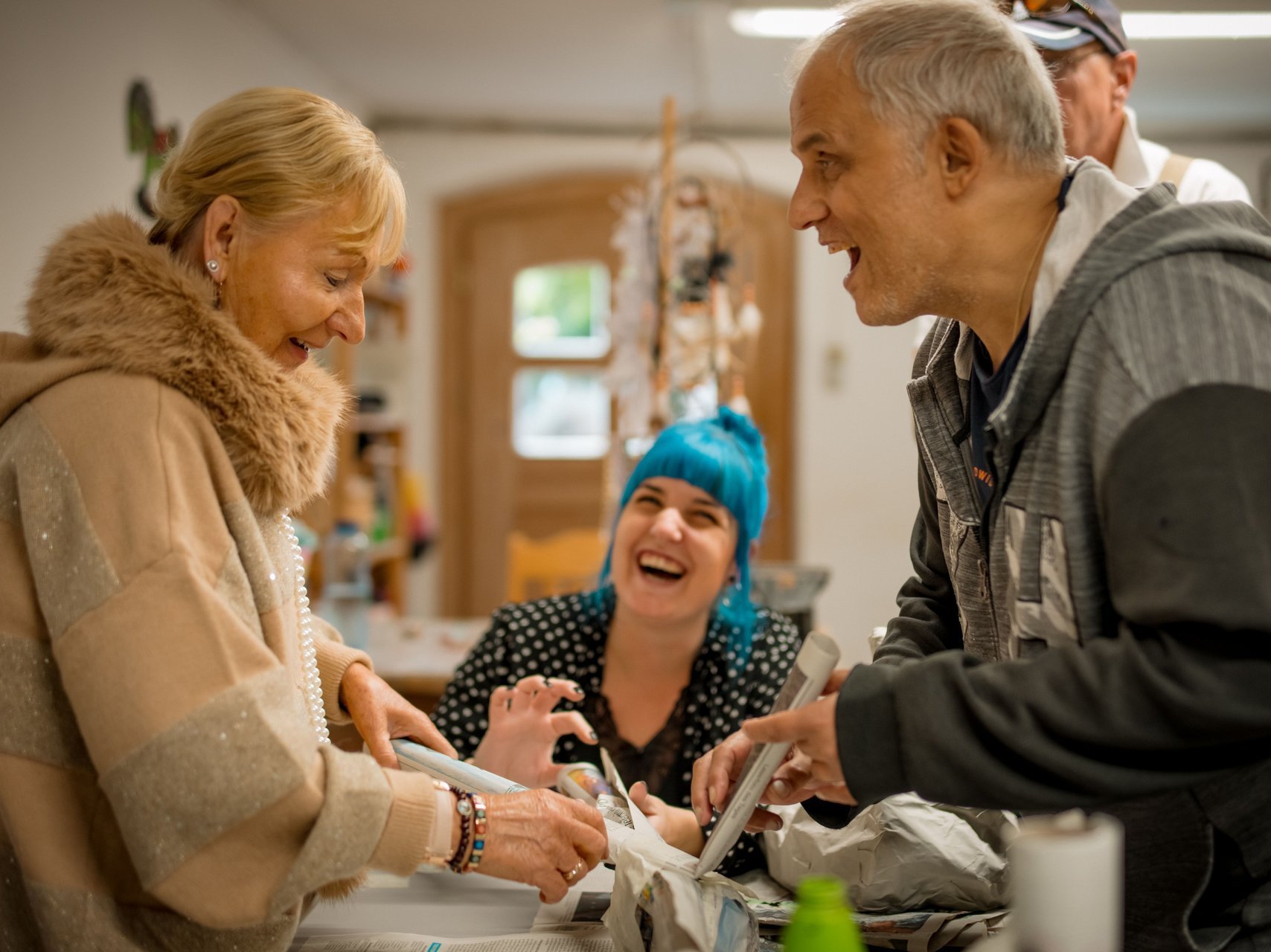 Eine Gruppe Bewohnenden klebt mit viel lachen ein Kreativprojekt aus Zeitungspapier zusammen.