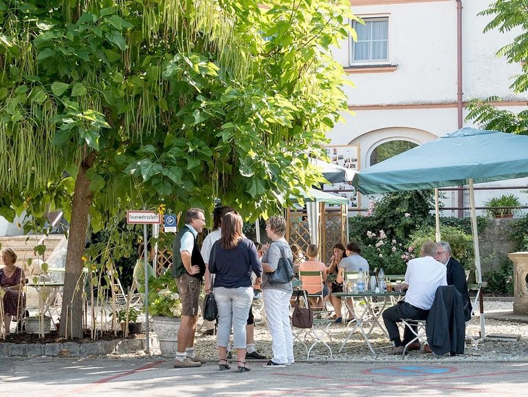 Innenhof der Suchthilfe: Sitzen wie im Biergarten mit Sonnenschirm und unter Bäumen