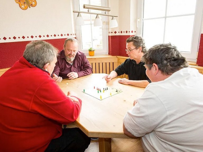 Vier Männer beim "Mensch ärgere Dich nicht" spielen