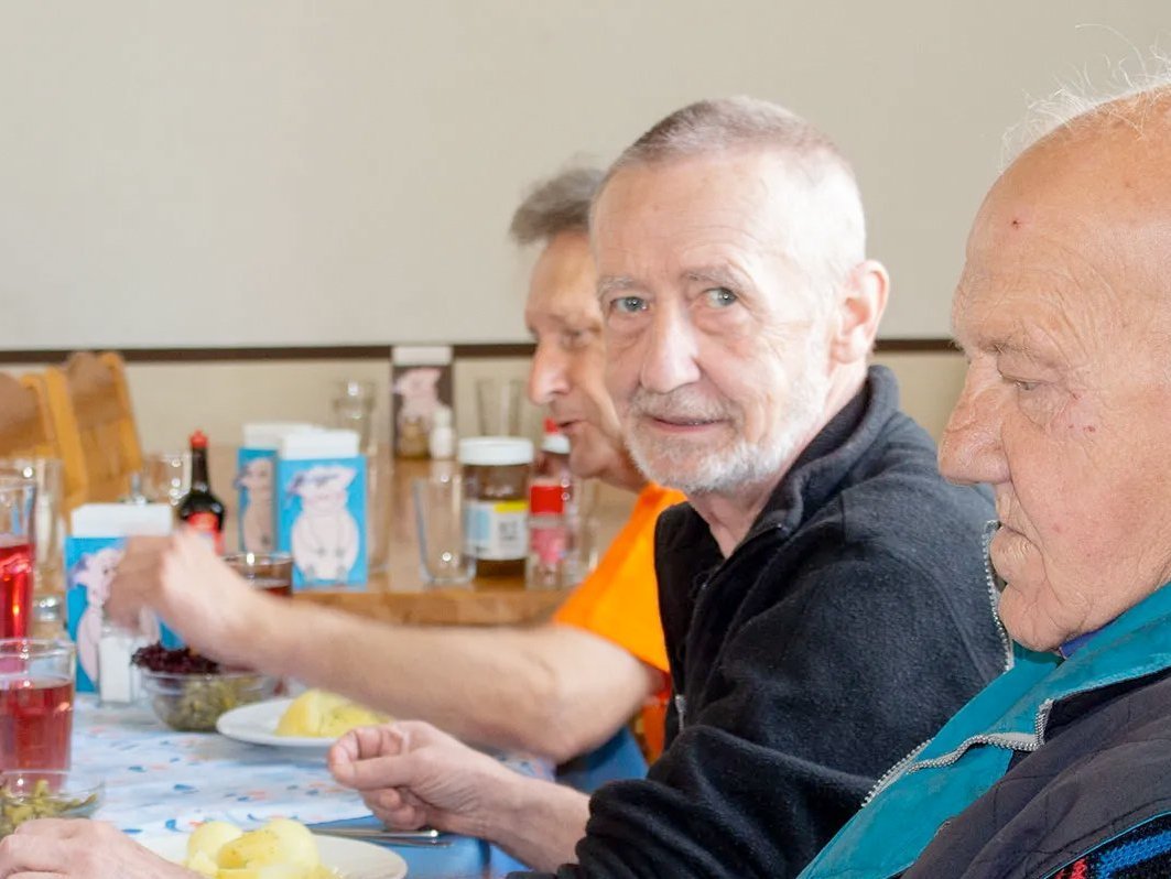 Drei ältere Männer sitzen nebeneinander am Tisch beim Essen - es gibt Salzkartoffeln und Salat 