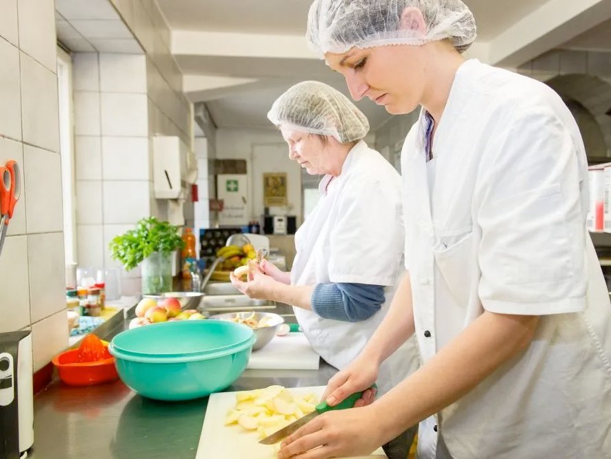 konzentriert schälen und schneiden zwei Köchinnen Äpfel an einer Arbeitsplatte der Küche 