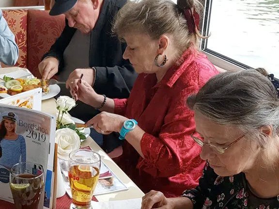 Gruppe älterer Frauen und Männer beim gemeinsamen Essen (paniertes Schnitzel mit Kartoffelsalat)