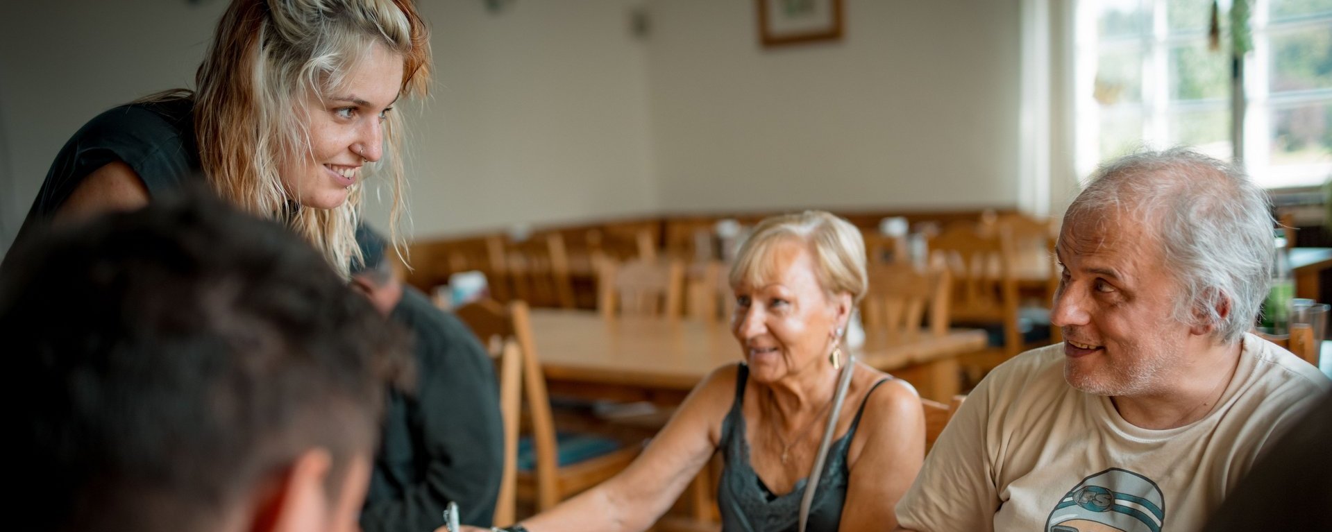 Bewohnende sitzen zusammen an einem Tisch und füllen mit viel Freude ein Kreuzworträtsel aus.